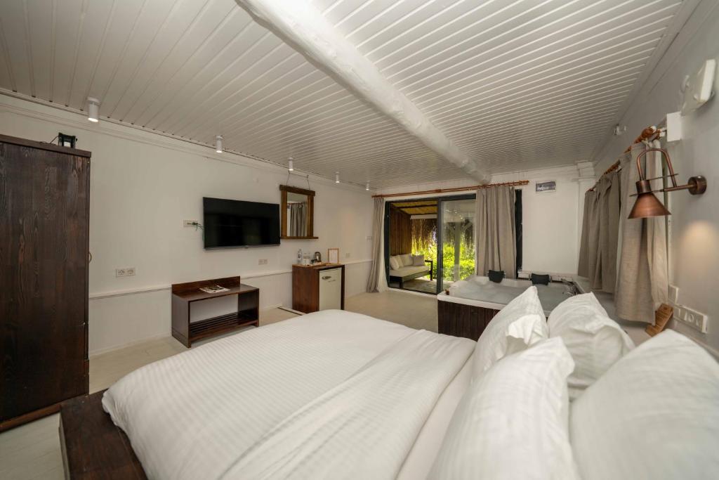 a bedroom with a large white bed and a television at Lov Faralya Adults Only in Faralya