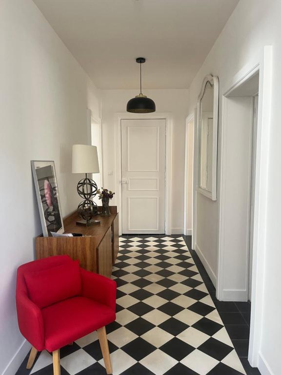 Una habitación con una silla roja y un suelo a cuadros. en Gare - Visitation grand Appartement , 1 chambre, en Angers