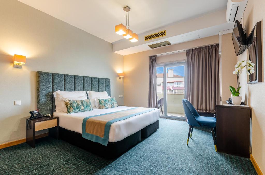 A bright double room with a desk, window, air conditioning and wall-mounted television.