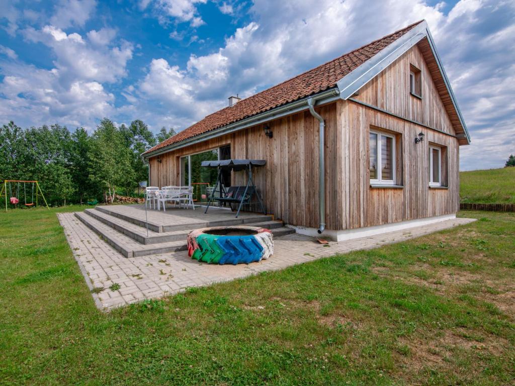 mały drewniany dom z placem zabaw przed nim w obiekcie Holiday Home Zagroda nad Krutynią by Interhome w mieście Spychowo