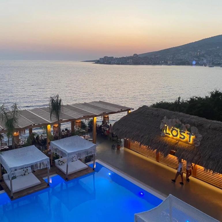 alost restaurant with a view of the water at dusk at Sarande Barracuda View Apartment in Sarandë
