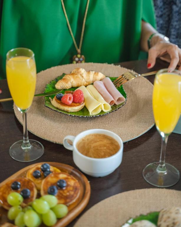 A full breakfast table with pastries, cold cuts, fruit, coffee and orange juice.