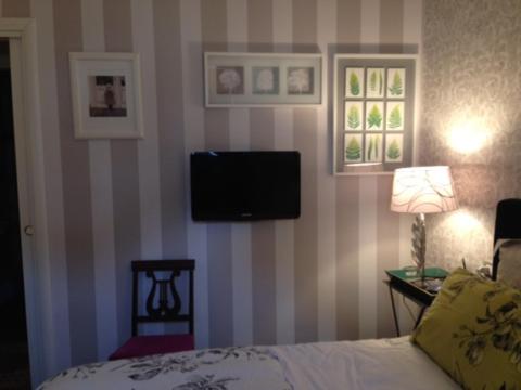 a bedroom with a bed and a tv on a striped wall at La Finestra Sul Cortile in Aosta