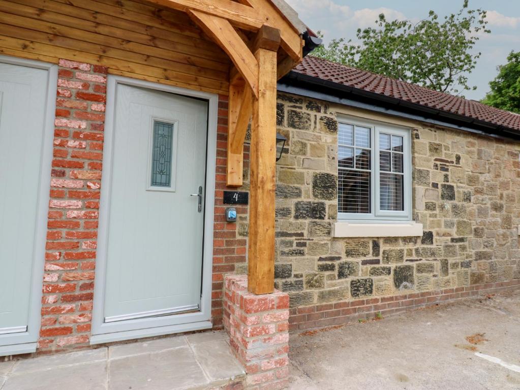 ein Backsteinhaus mit einer weißen Tür und Fenstern in der Unterkunft Cosy Cottage 4 in Durham