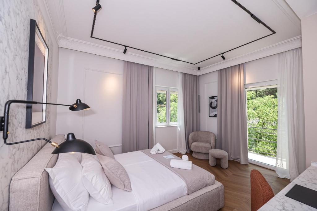 ein weißes Schlafzimmer mit einem Bett und einem Stuhl in der Unterkunft Estium Heritage Rooms in Zadar