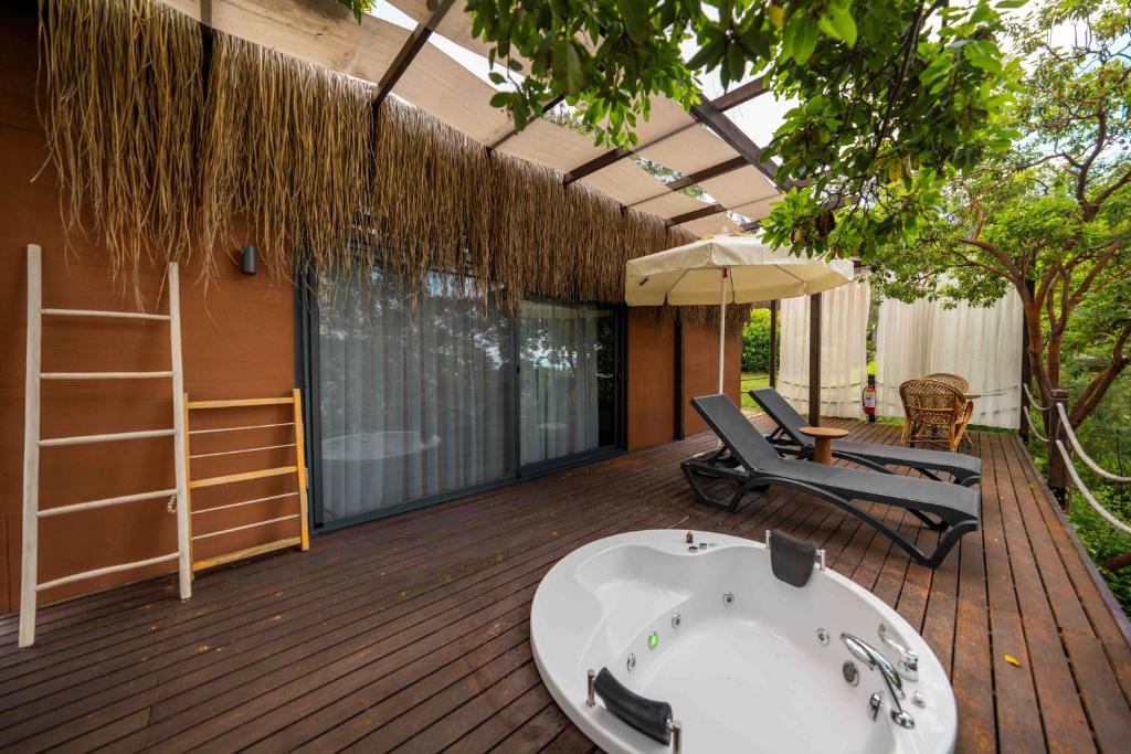 a deck with a hot tub and chairs and an umbrella at Lov Faralya Adults Only in Faralya