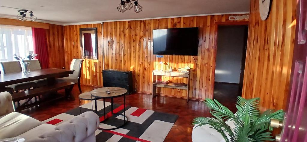 a living room with wooden walls and a piano at Mi casa, tu casa in Punta Arenas