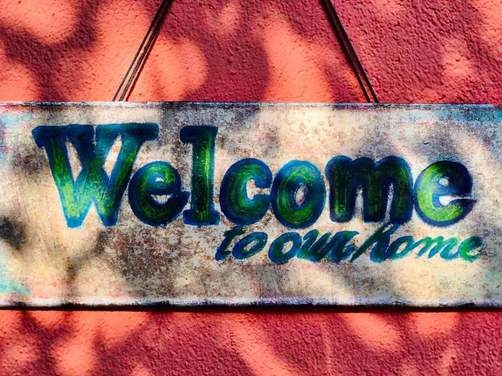a sign on a wall with the words welcome welcome at Нашата къща in Sinemorets