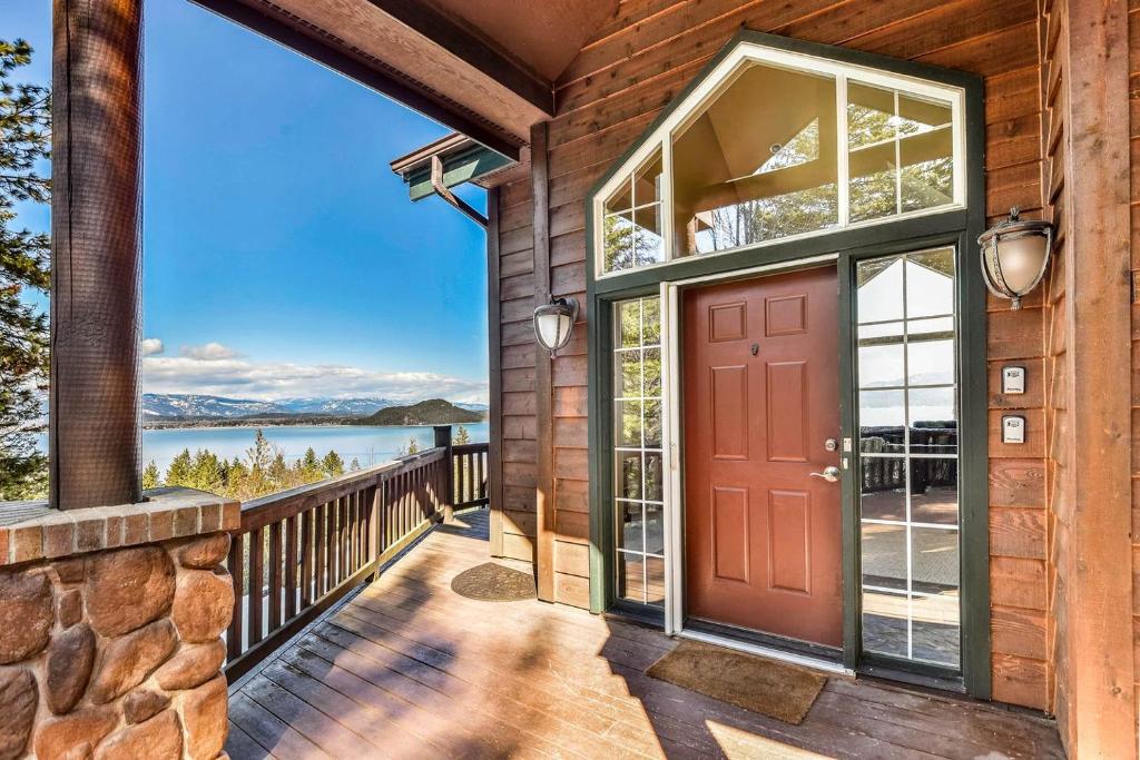 a home with a red door and a view of the water at Majestic Summit Retreat: Family Vacation Rental Overlooking Lake Pend Oreille in Lignite