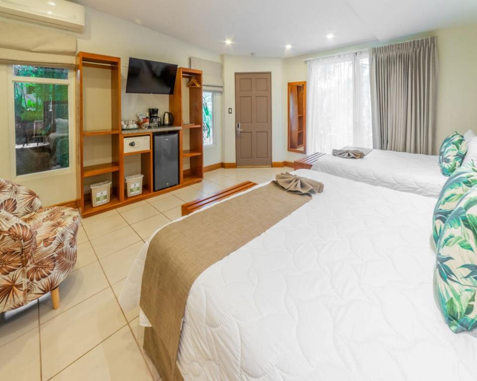 a large bedroom with two beds and a television at Hotel & Spa Poco a Poco - Costa Rica in Monteverde Costa Rica