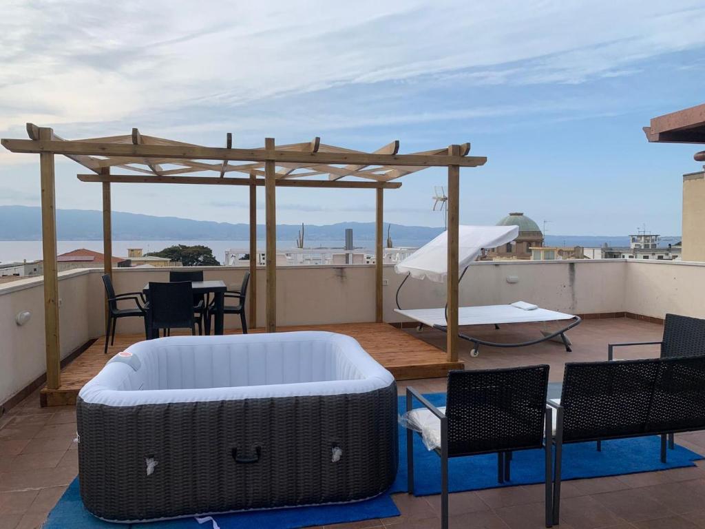 a patio with a hot tub and chairs on a roof at luxury ciccy apartment in Reggio di Calabria