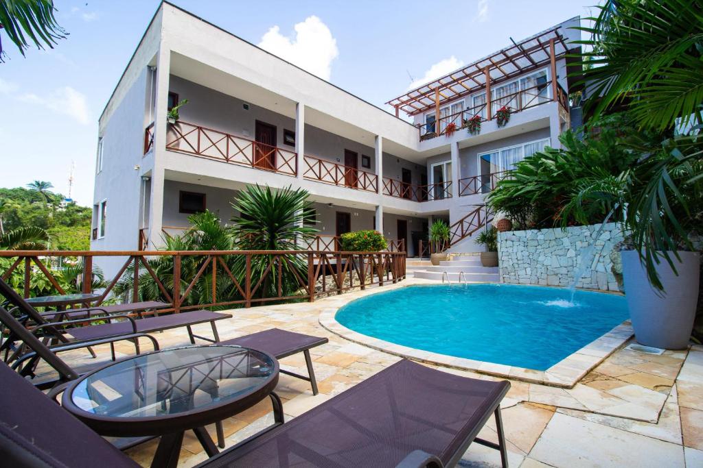 a hotel with a swimming pool and patio furniture at Charme Pousada Boutique & Spa in Morro de São Paulo