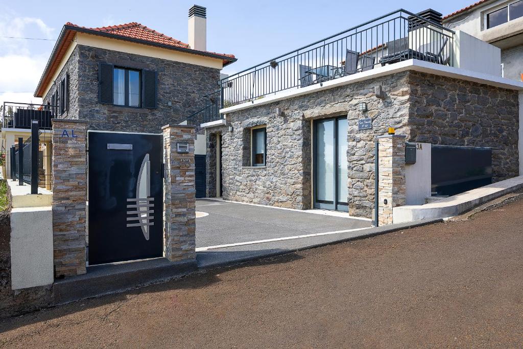 ein Backsteinhaus mit schwarzer Tür auf einer Straße in der Unterkunft Casa Pimenta in Fajã da Ovelha in Prazeres