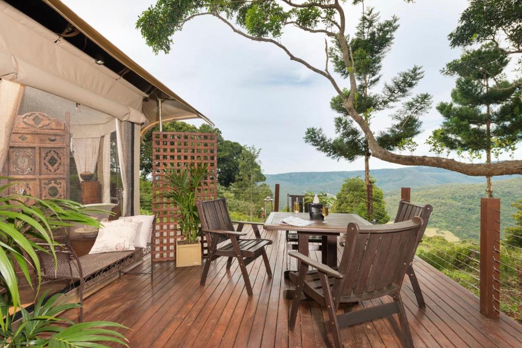 una terraza al aire libre con mesa, sillas y vistas. en Clouds Safari en Beechmont
