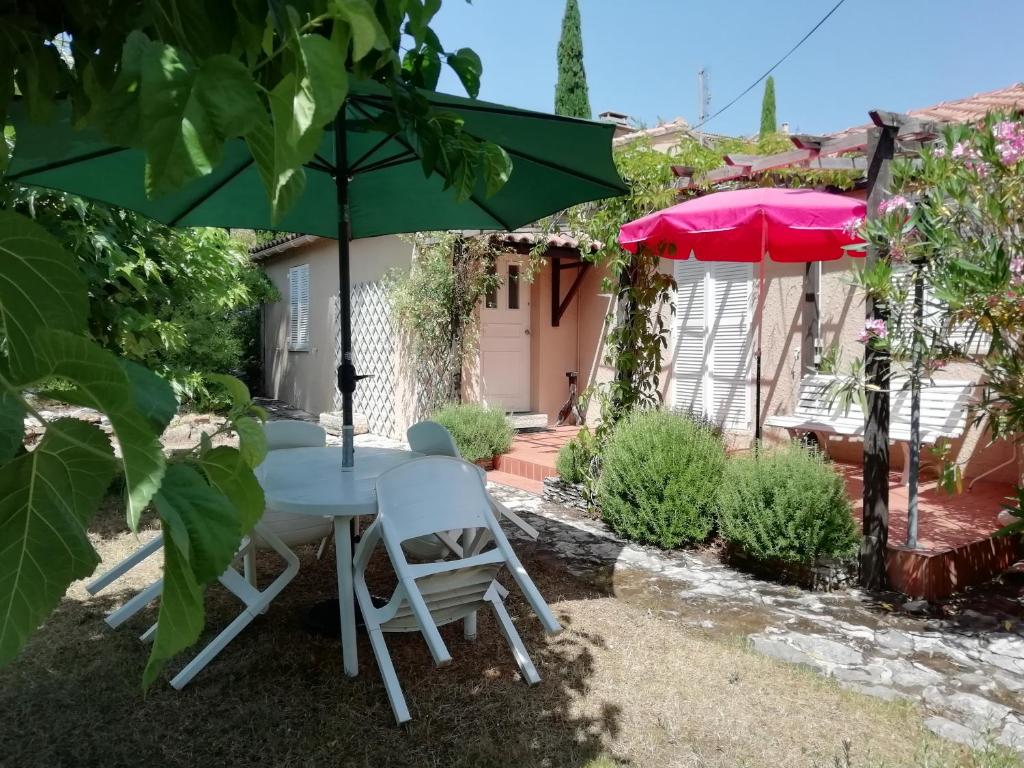 een tafel en stoelen onder een parasol in een tuin bij Maison Charrasse in Flassan