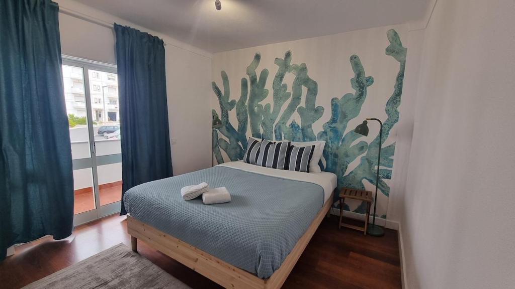 ein Schlafzimmer mit einem Bett mit einem Kaktus-Wandbild in der Unterkunft Ericeira Breeze Villa in Ericeira