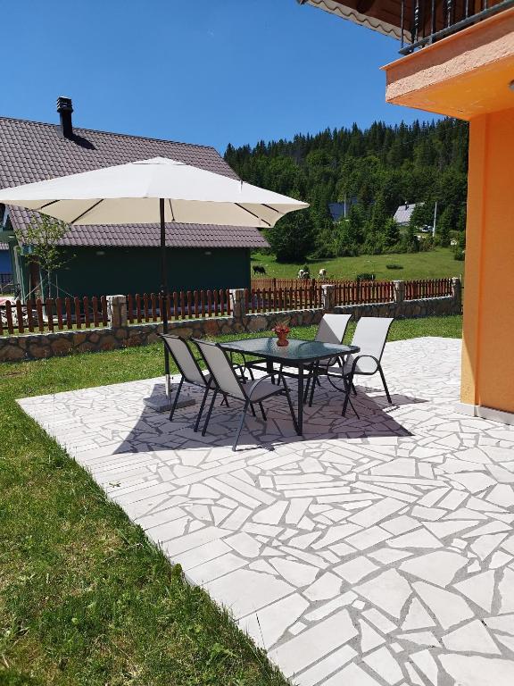 a patio with a table and chairs and an umbrella at Durmitor Sunstone in Žabljak