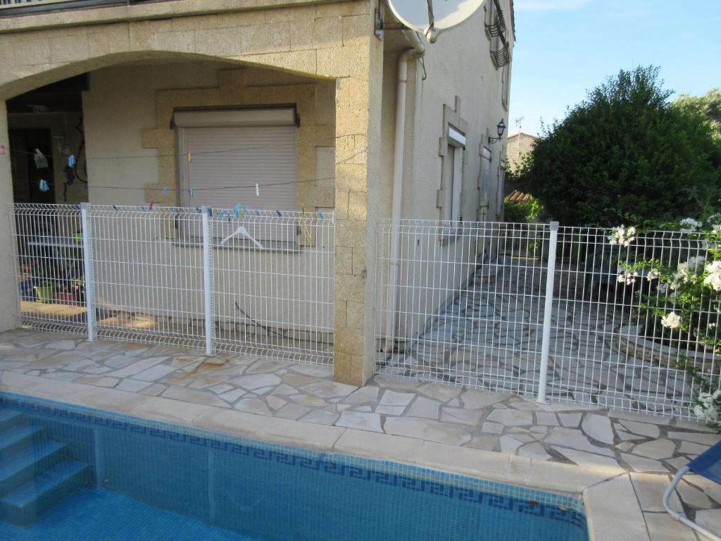 a fence in front of a house with a pool at T3 clim 4 pers terrasse jardin piscine in Coursan