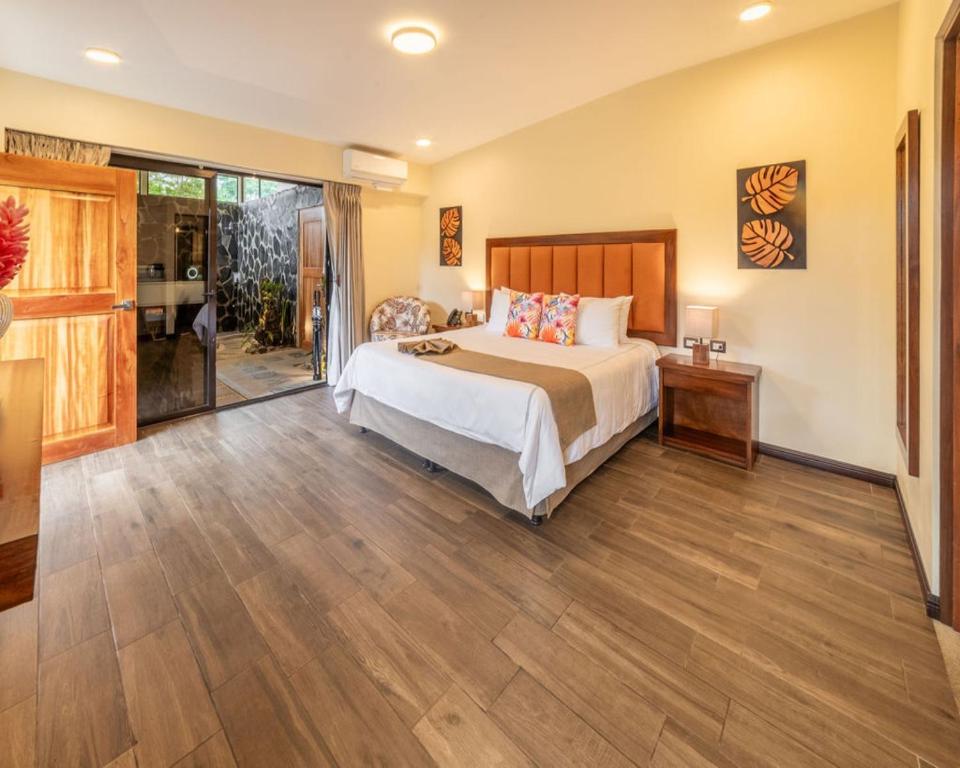 a bedroom with a bed and a wooden floor at Hotel & Spa Poco a Poco - Costa Rica in Monteverde Costa Rica