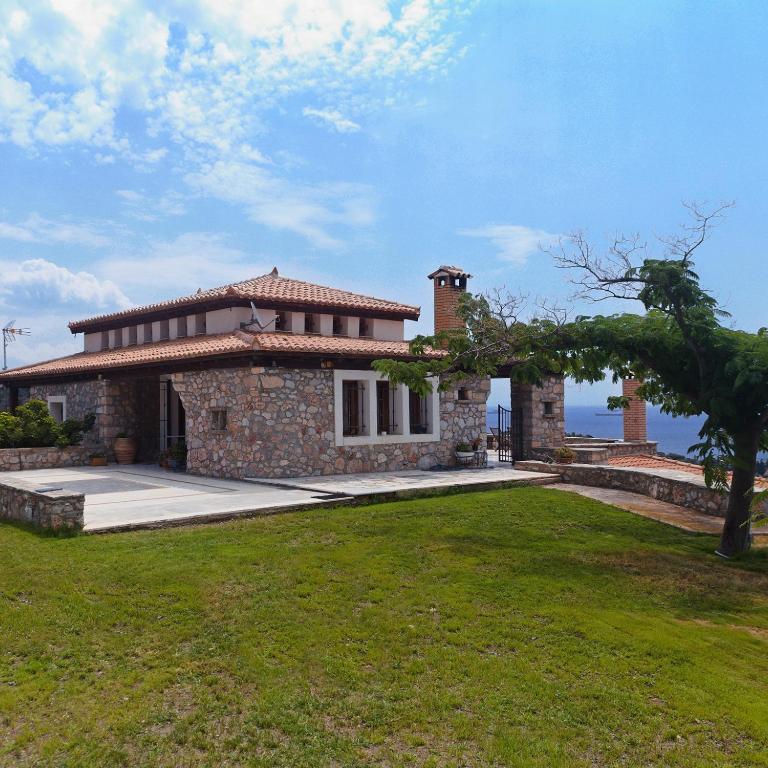 a large stone house with a grass yard at Olivia Country House in Panayía