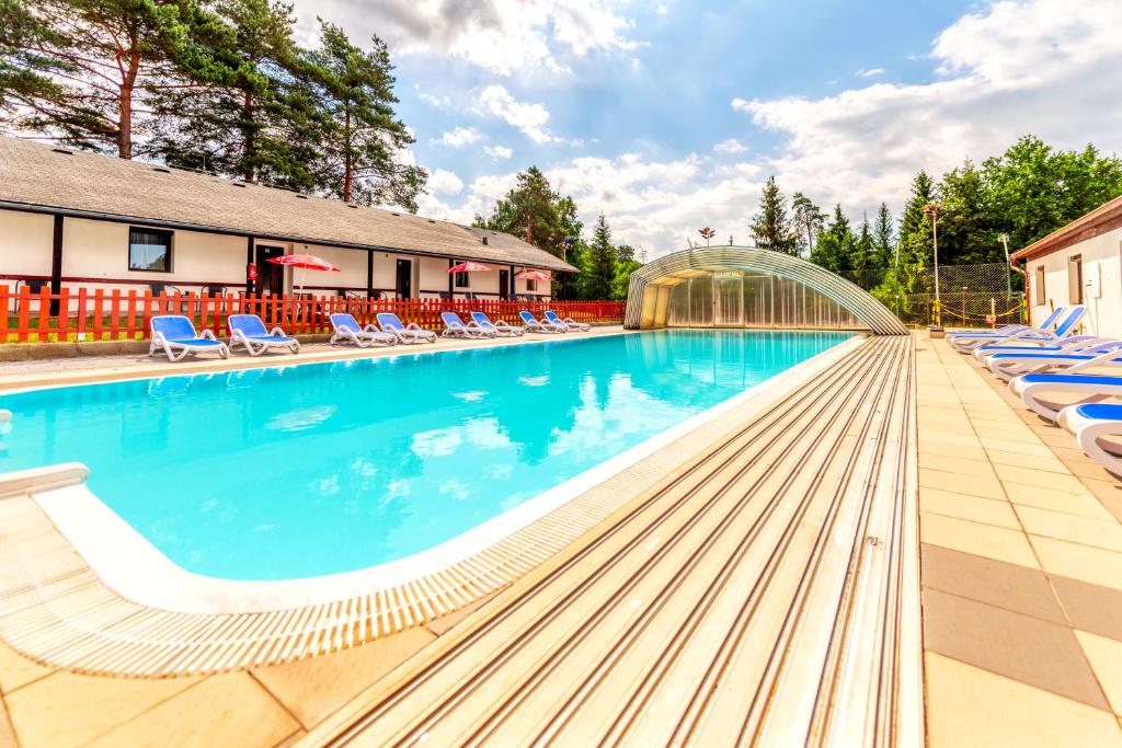 a swimming pool with lounge chairs and a building at RÁJ sportovní a rekreační resort Branžež-All inclusive in Kněžmost