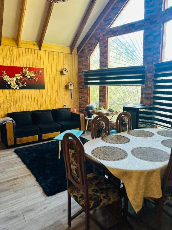 a living room with a table and chairs and a couch at Cabañas Alturas Chillan Benjamin in Recinto