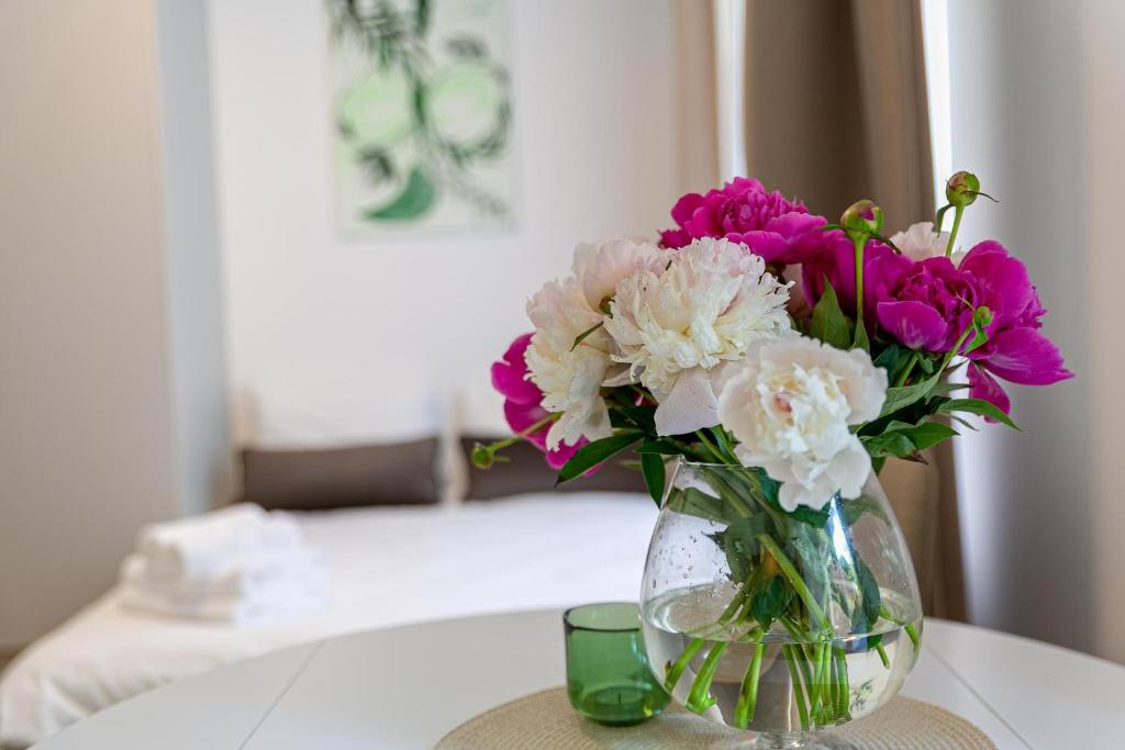 a vase filled with pink and white flowers on a table at Green Apartment with free parking in Kaunas
