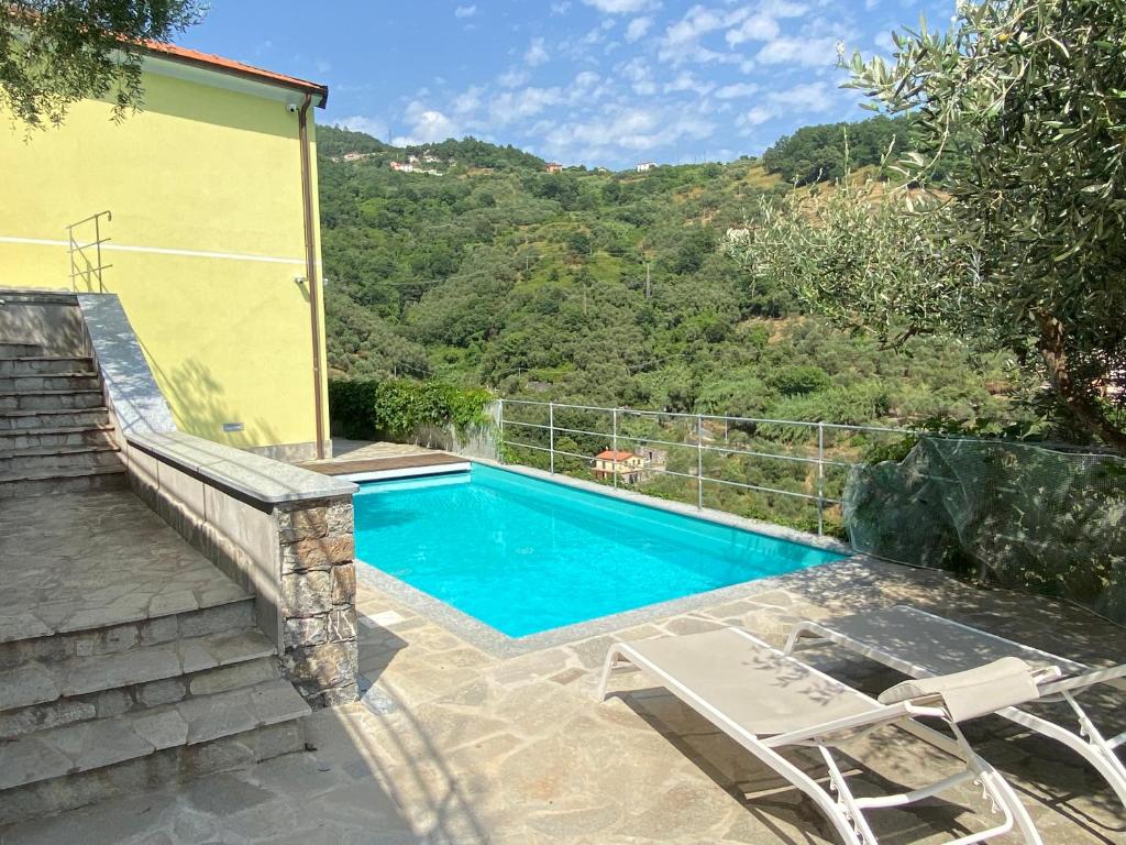 a swimming pool with two chairs next to a house at House in Paradise in Moneglia
