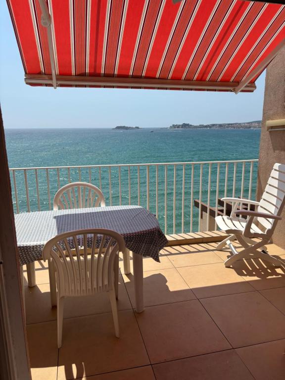 une table et des chaises sur un balcon avec l'océan dans l'établissement Studio Kamarina, à Sanary-sur-Mer