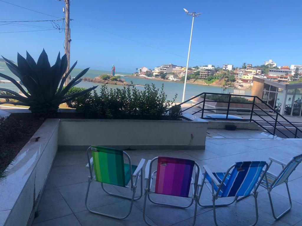 three chairs sitting on a patio with a view of the ocean at Apartment Pé na Areia - Guarapari in Guarapari
