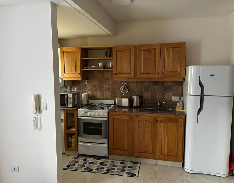 a kitchen with wooden cabinets and a white refrigerator at Depto centrico soñado in San Martín de los Andes