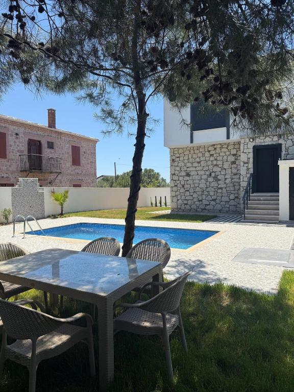 a table and chairs next to a swimming pool at Luxury Villa with Pool Near Sarimsakli Beach in Ayvalık