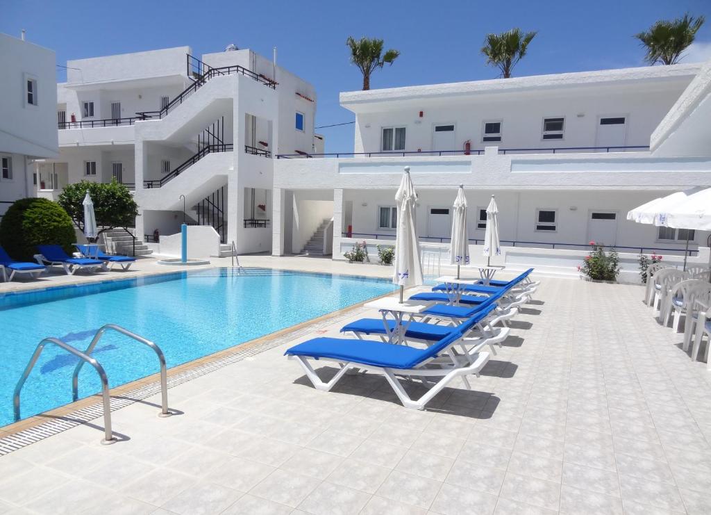 basen z niebieskimi leżakami i parasolami w obiekcie Michalis Studios & Apartments w mieście Kos