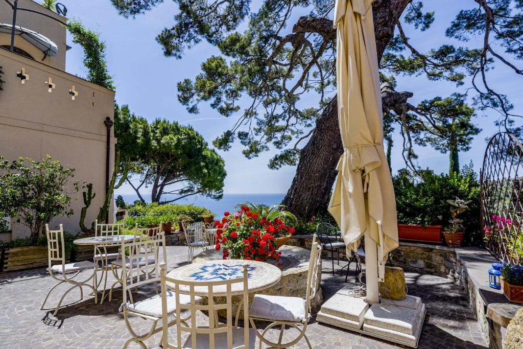a patio with tables and chairs and an umbrella at Uliveto Saglietto Agriturismo a Poggi Apartments in Imperia