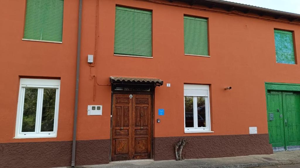 an orange building with green windows and a wooden door at Casa Esther and Pepe VUT LE884 in Riego de la Vega