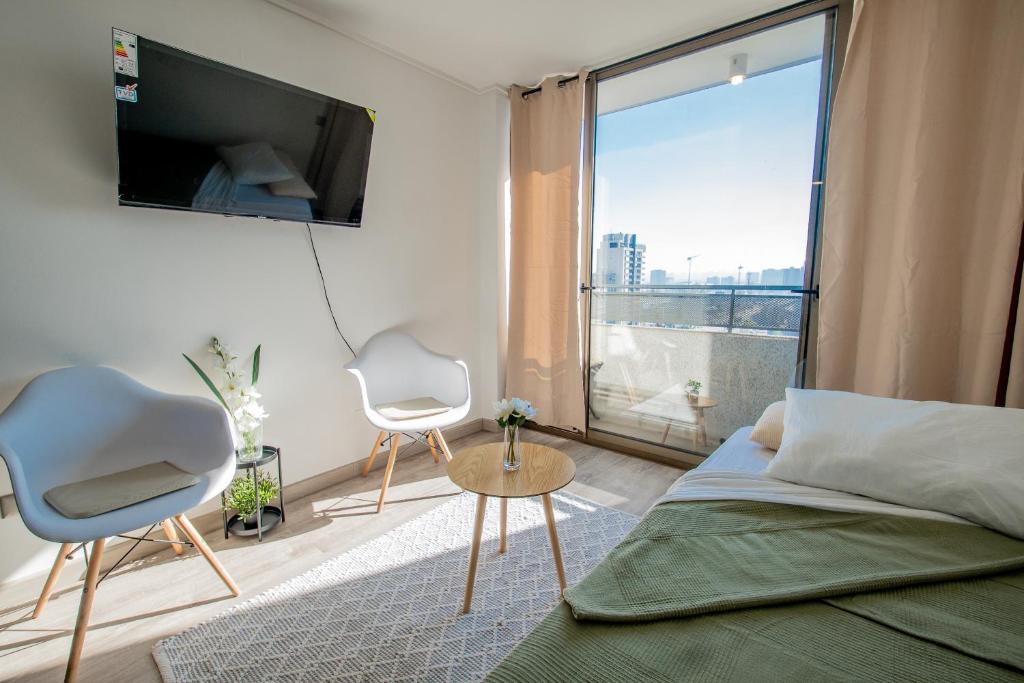 Un dormitorio con una cama y dos sillas y un televisor. en Loica Host - Smart, en Santiago