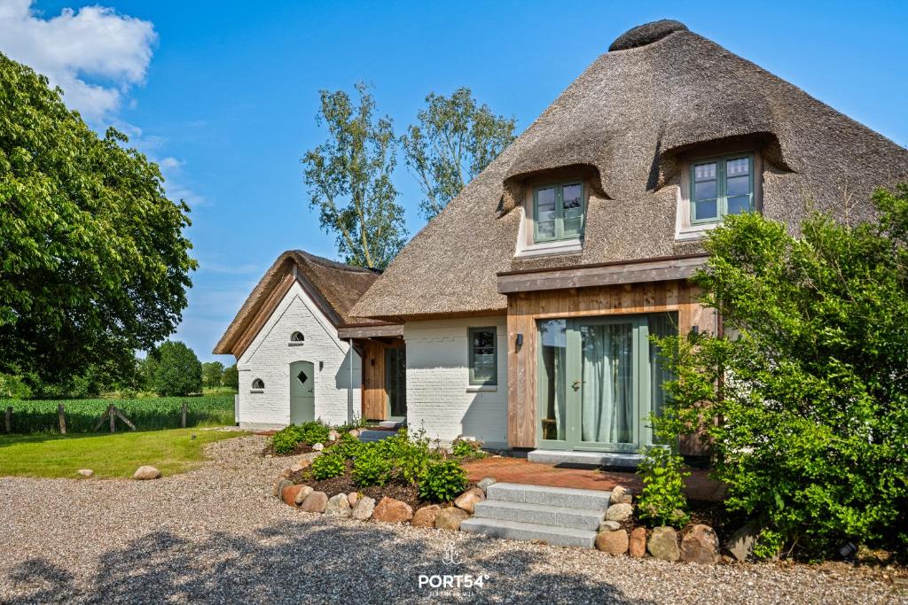 Ce cottage dispose d'un toit de chaume et d'une cour. dans l'établissement Ferienhaus ReetCottage 24 Dörphof, à Dörphof