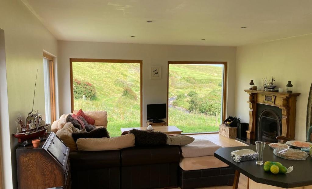a living room with a couch and a large window at Glenurla Valley Cottage in Ballycastle