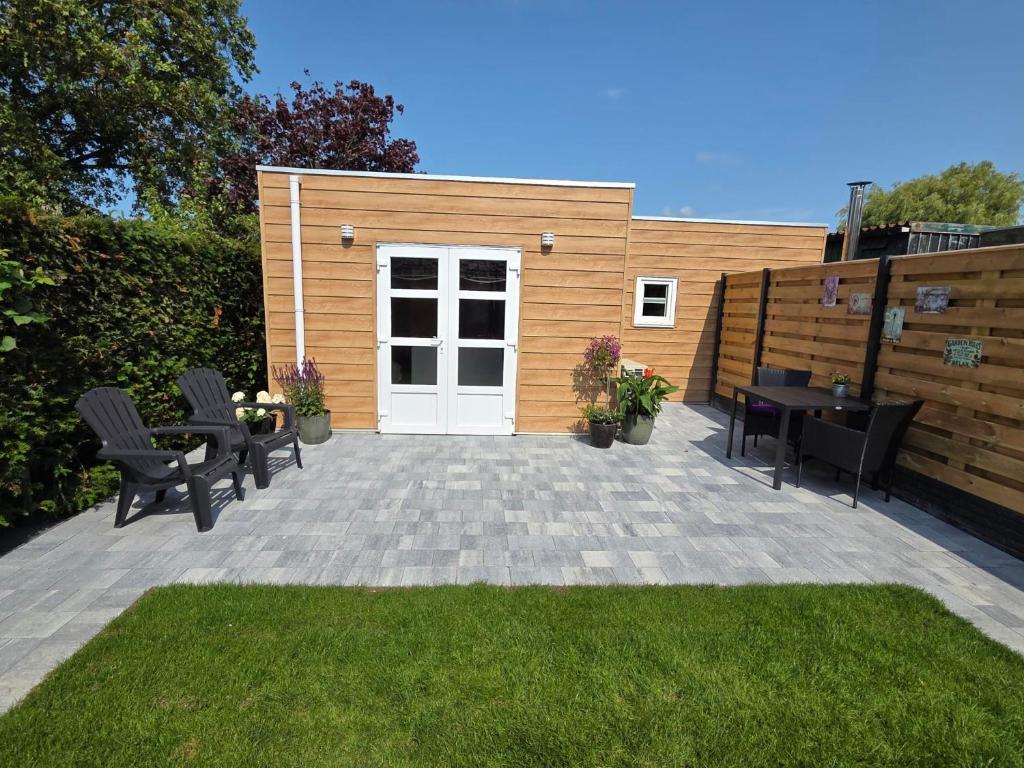 a patio with chairs and a table and a white door at Nieuwe vakantie woning Serooskerke in Serooskerke