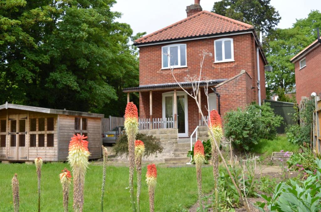 a brick house with flowers in the yard at Friarscroft Lodge Holiday Home in Wymondham