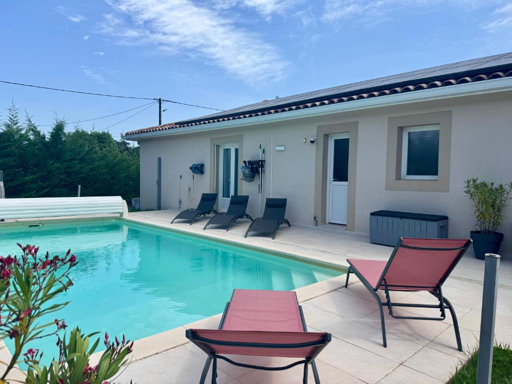 ein Swimmingpool mit Stühlen und ein Haus in der Unterkunft Villa avec piscine in Landorthe