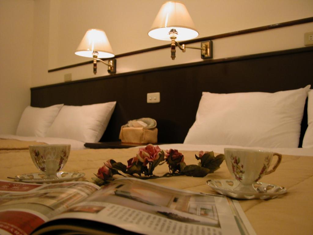 a table with two cups and a book on a bed at Relax heart B&amp;B in Dongshan
