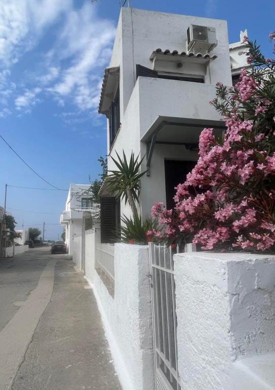 a white building with pink flowers on the side of it at Cozy house by the sea in Batsi