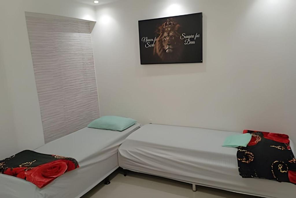 Dos camas en una habitación con un cuadro en la pared. en Apart Rio de janeiro prox. praia, en Río de Janeiro