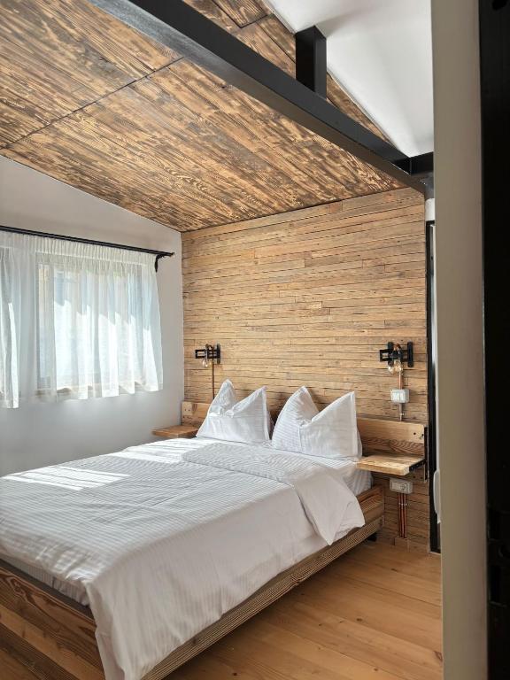 a bedroom with a large bed with a wooden wall at Stone Village Transfagarasan in Oeștii Ungureni