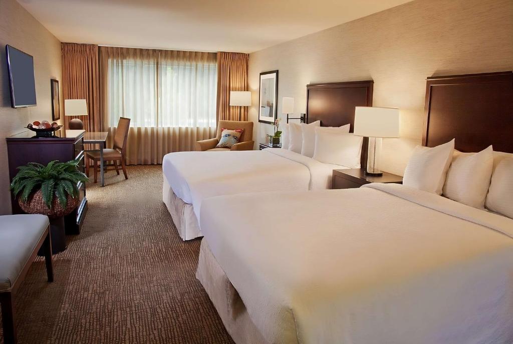 ein Hotelzimmer mit zwei Betten und einem Schreibtisch in der Unterkunft Eastgate Hotel - BW Signature Collection in Bellevue