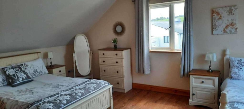 ein Schlafzimmer mit einem Bett, einer Kommode und einem Spiegel in der Unterkunft Tranquil Retreat at Ailt Cottage in Dunfanaghy