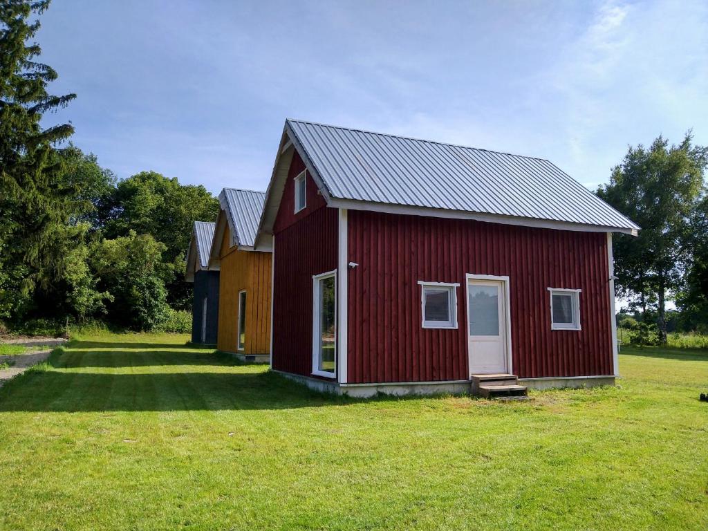 a red barn with a white door in a field at Agroturystyka Kozianka in Iława