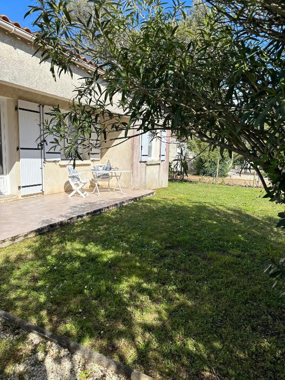 a patio with a table and a chair in a yard at La Jalé in Saint-Georges-dʼOléron