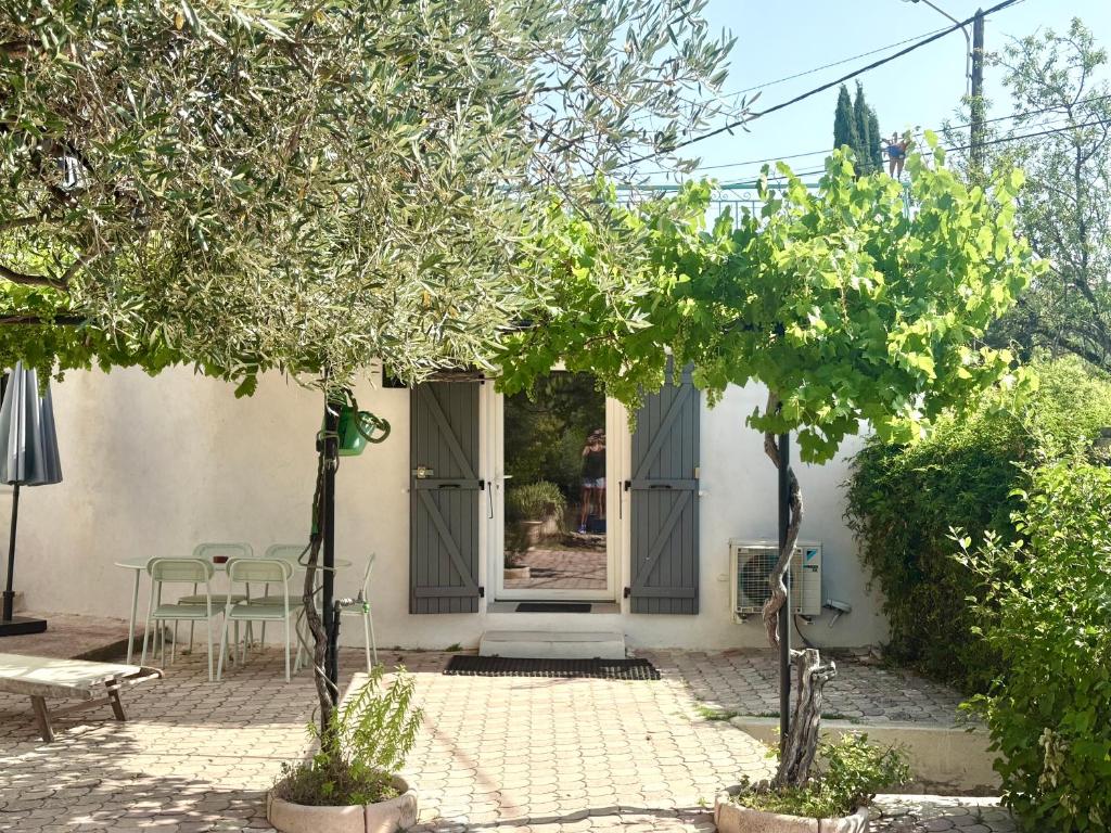 une terrasse avec des arbres, une table et des chaises dans l'établissement Logement indépendant avec jardin classé par Gîte de France, à Allauch